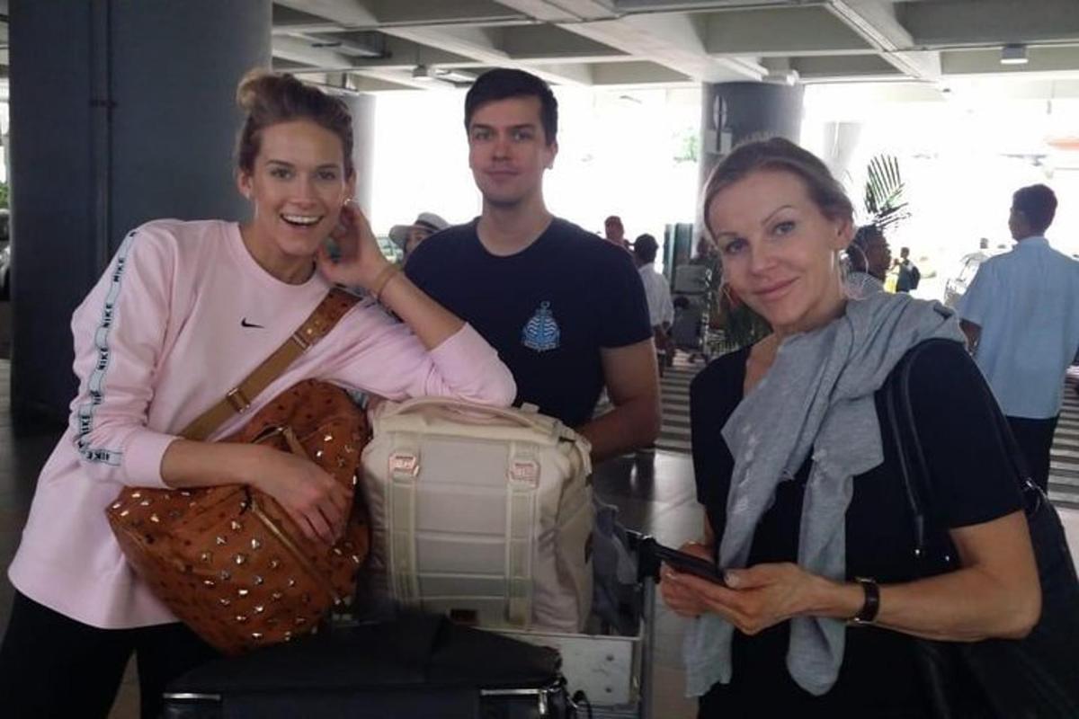 Dos mujeres y un hombre de pie junto a una mesa con una bolsa.