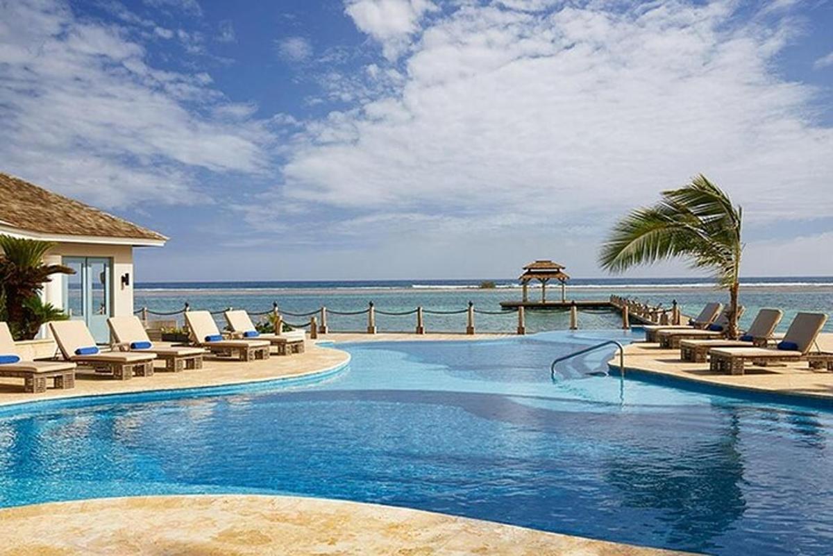una piscina con sedie e l'oceano sullo sfondo