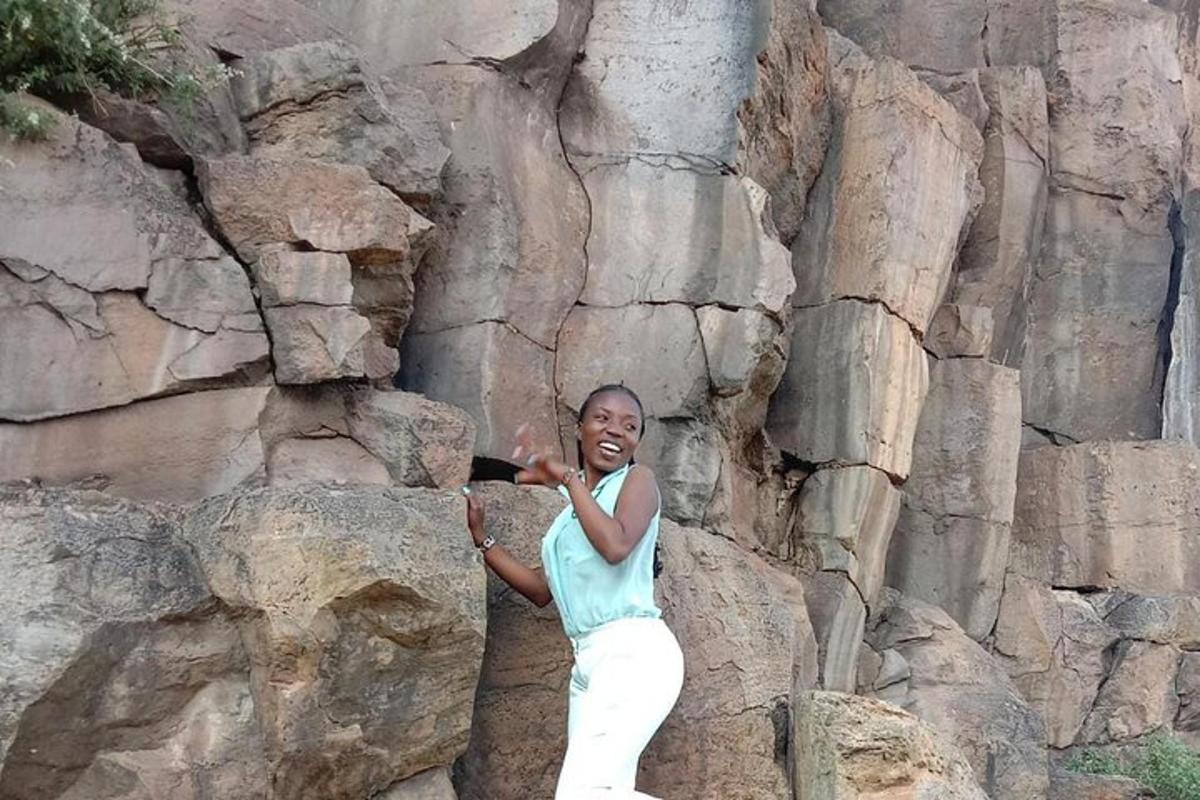 a woman standing next to a rock wall