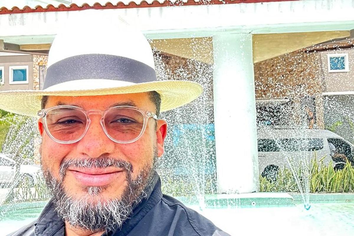 Un hombre con sombrero y gafas frente a una fuente.