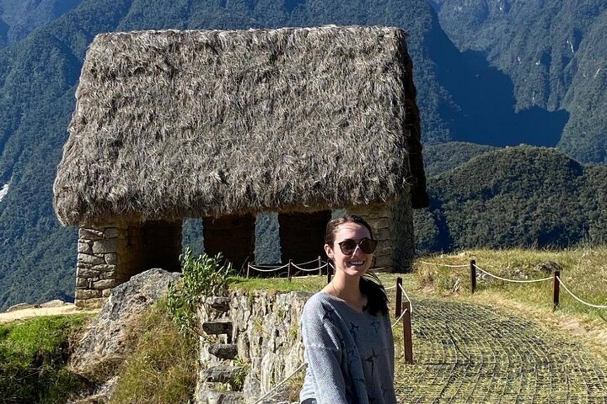una donna in piedi davanti a un edificio con il tetto di paglia