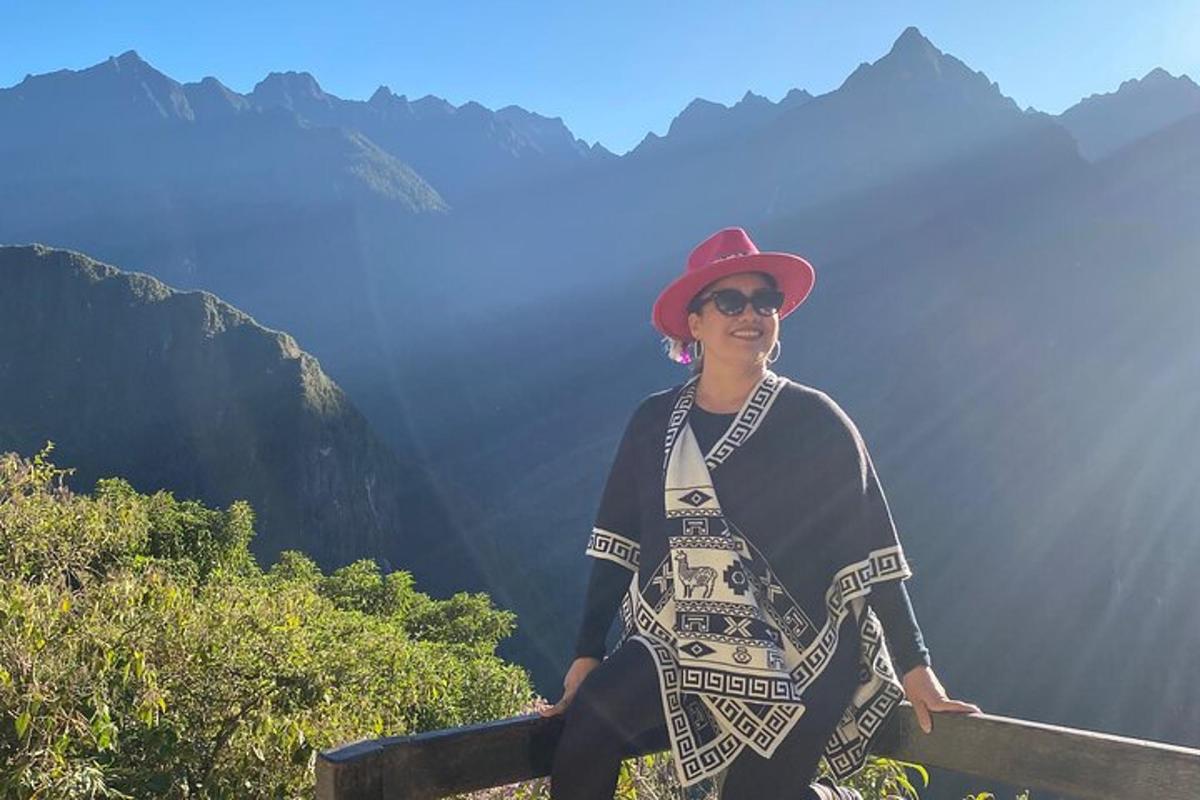 una donna seduta su una staccionata di fronte alle montagne