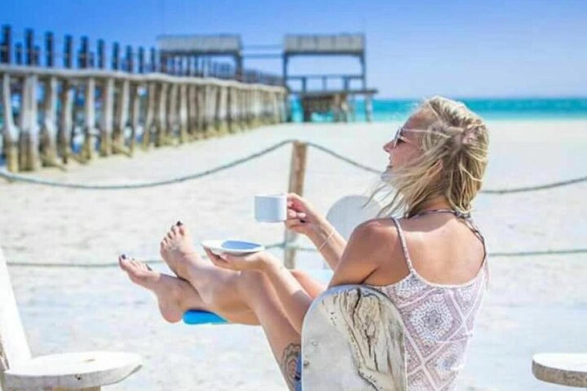 una donna seduta sulla spiaggia con una tazza di caffè