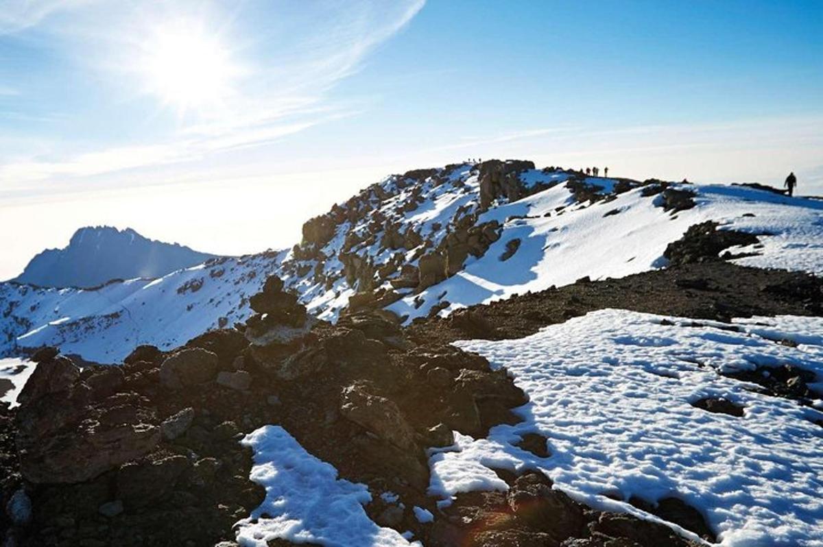 Snæþakið fjall með sólinni í bakgrunni