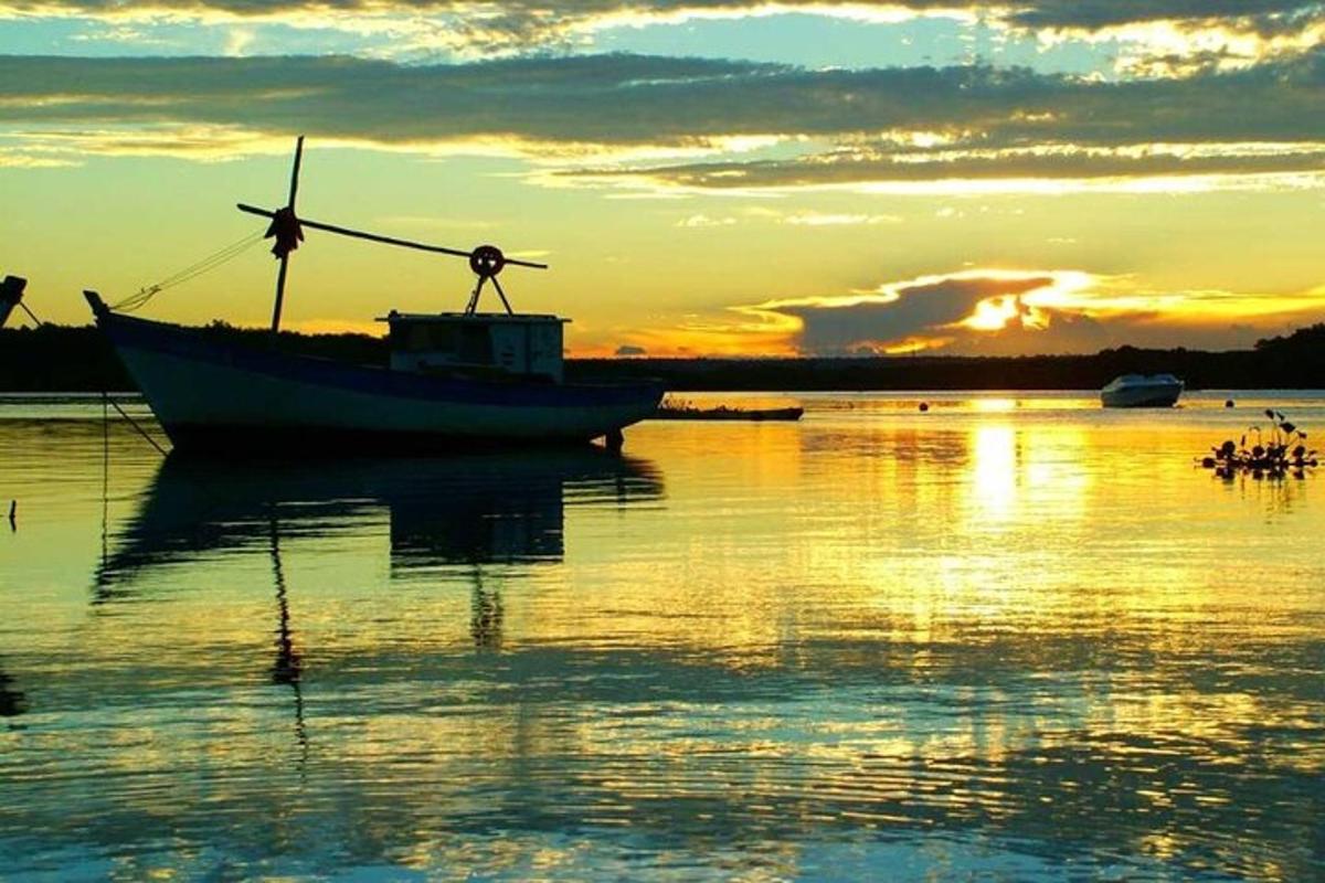 a boat sitting in the water at sunset