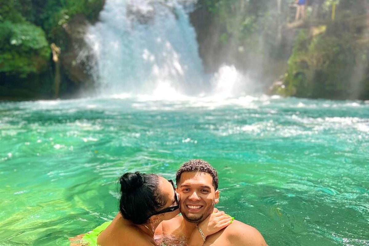 un uomo e una donna nell'acqua di fronte a una cascata