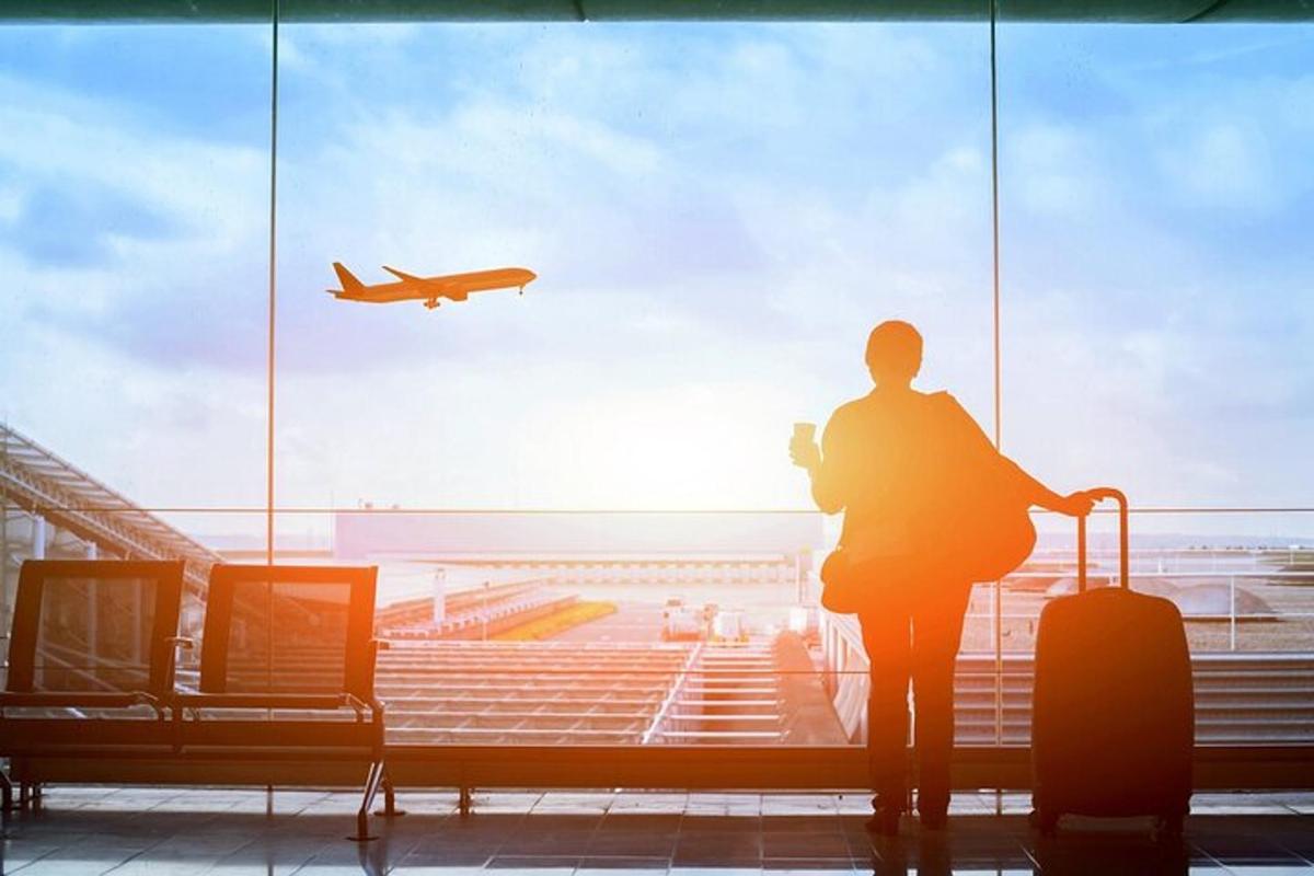 eine Person, die aus einem Flughafenfenster auf ein Flugzeug schaut