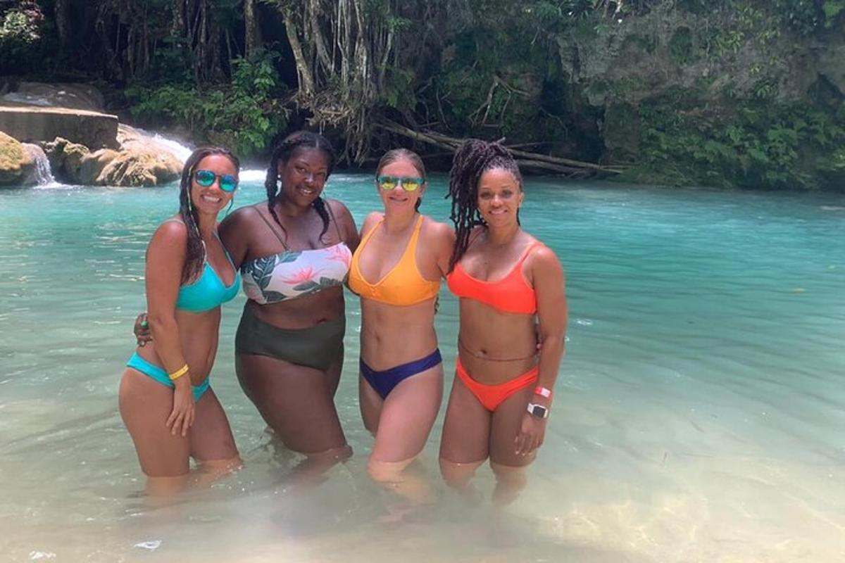 vier Frauen stehen im Wasser an einem Strand