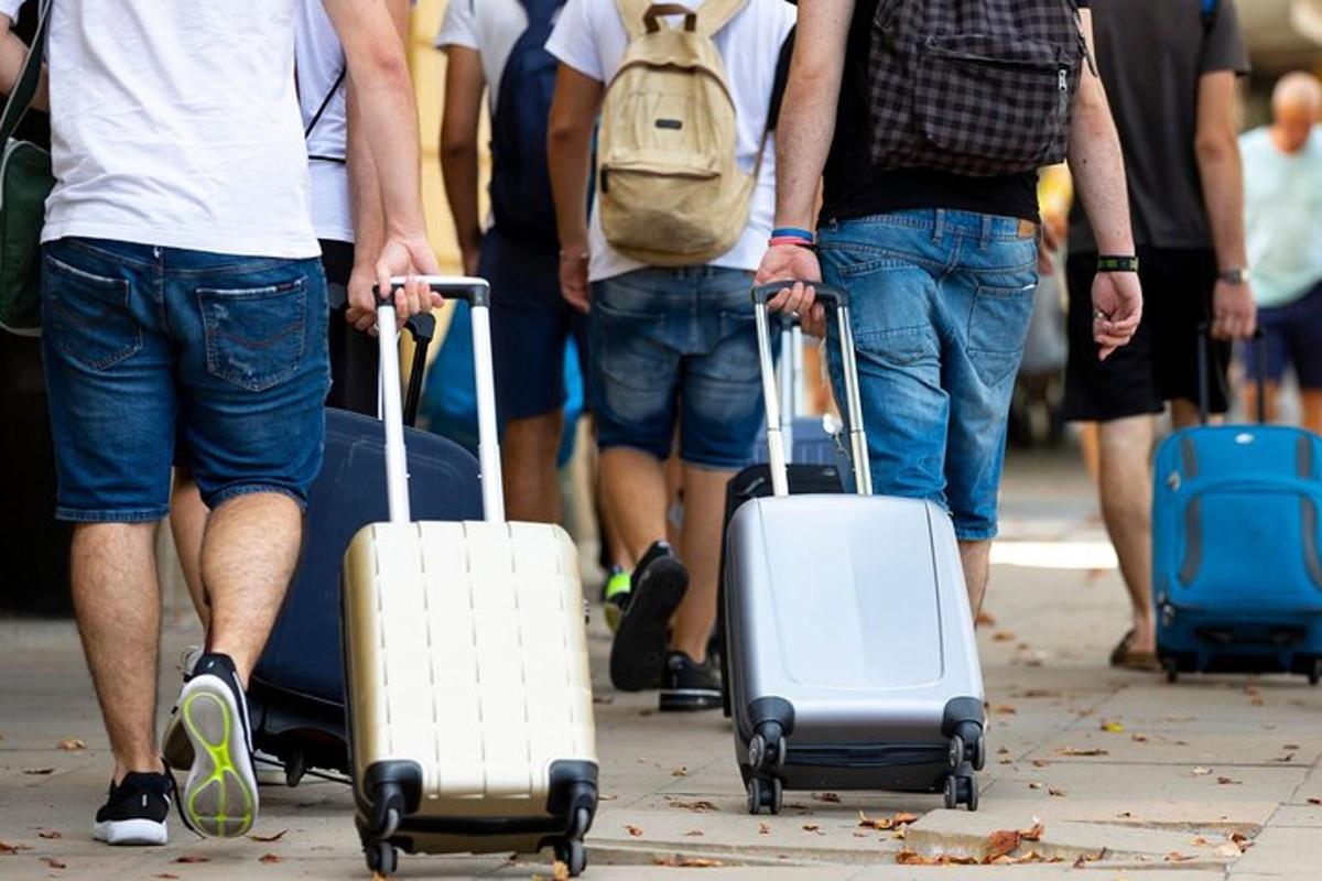 група людей, що йдуть вулицею зі своїм багажем