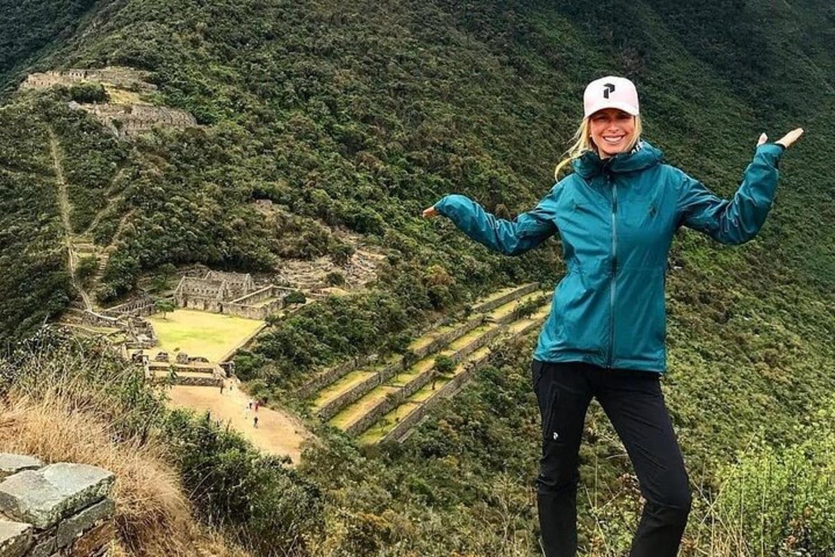 a woman standing on top of a mountain with her arms out