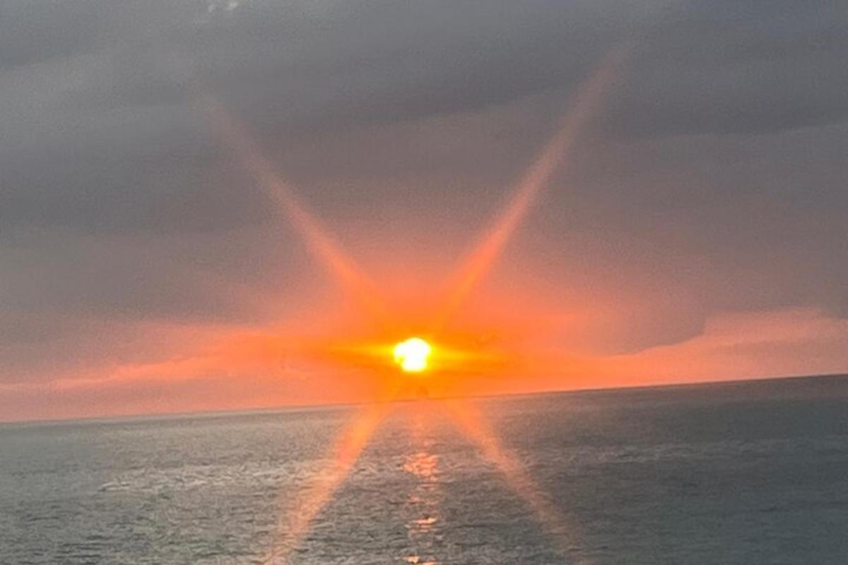 matahari terbenam di atas lautan dengan matahari di langit
