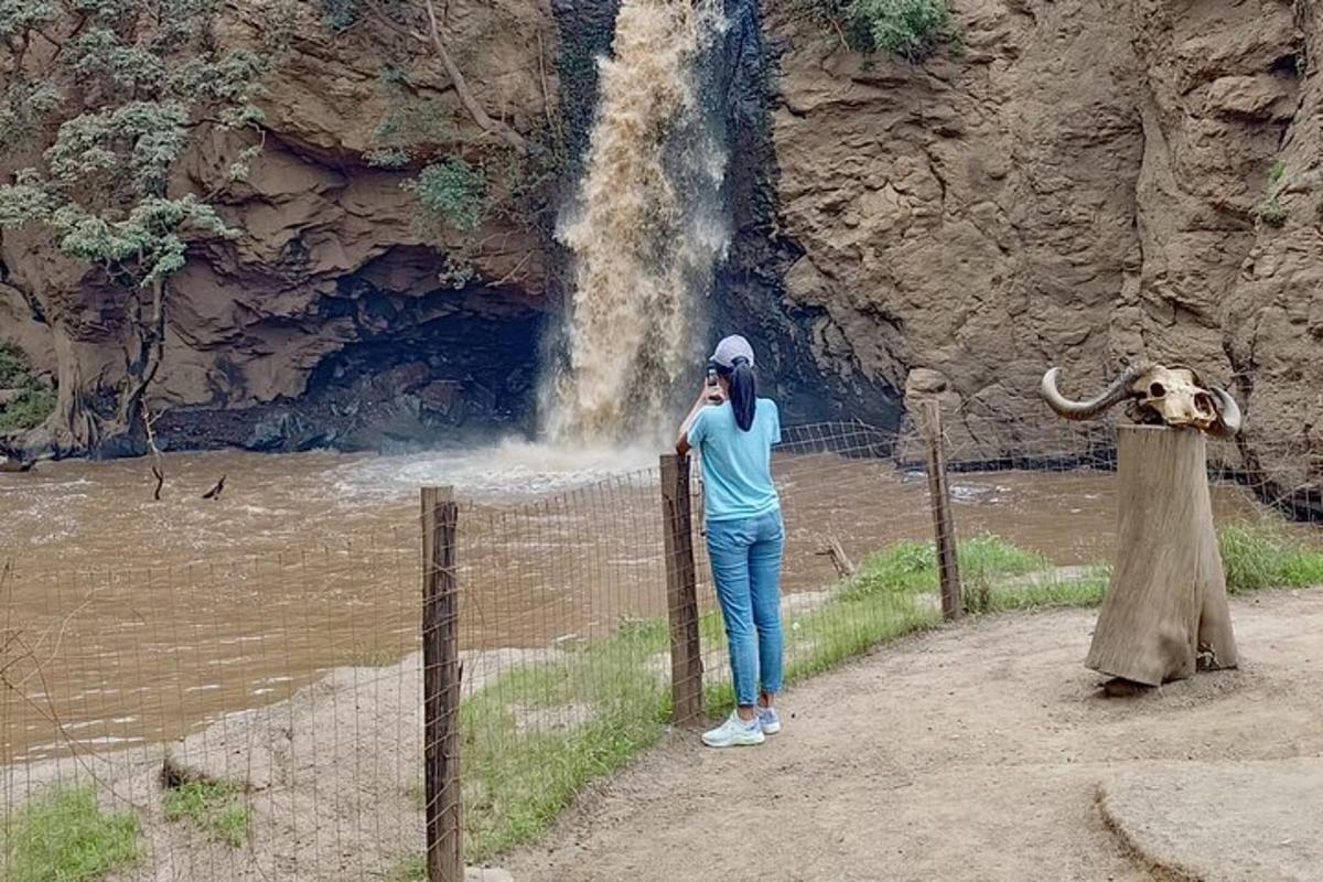 kona að tala í farsíma fyrir framan foss