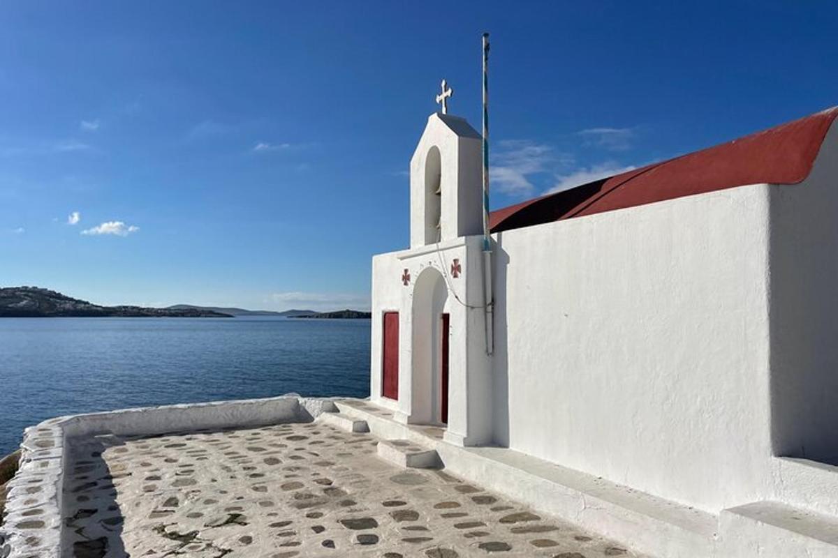 μια λευκή εκκλησία με έναν σταυρό στην άκρη του νερού