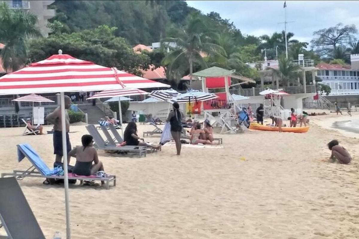 skupina lidí sedících na pláži se slunečníky