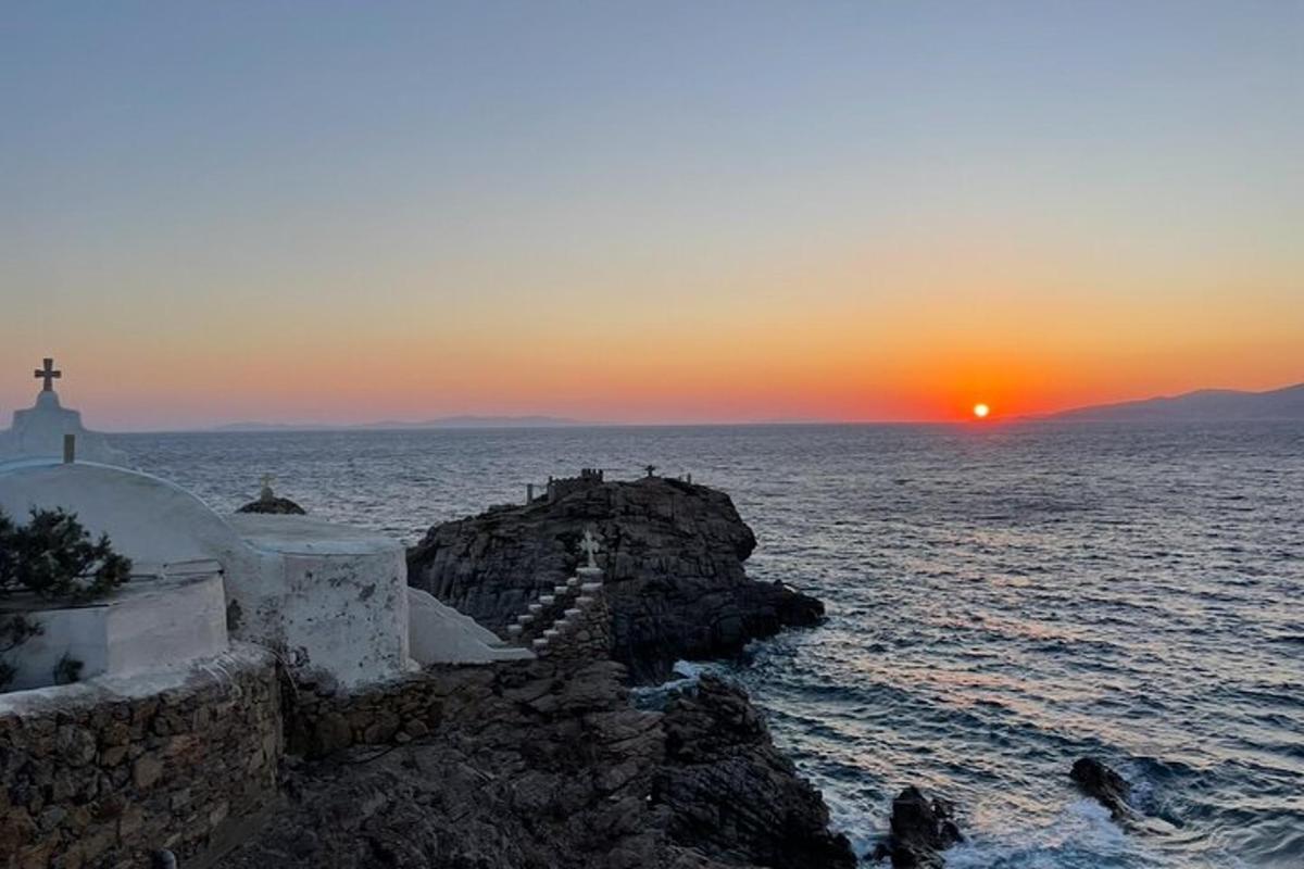 ein Sonnenuntergang über dem Wasser mit einer Kirche und dem Meer