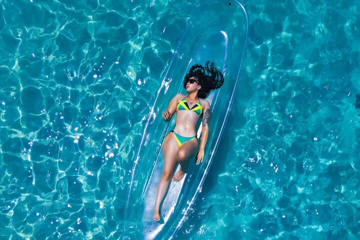 una dona en bikini nedant sobre una taula de surf en una piscina