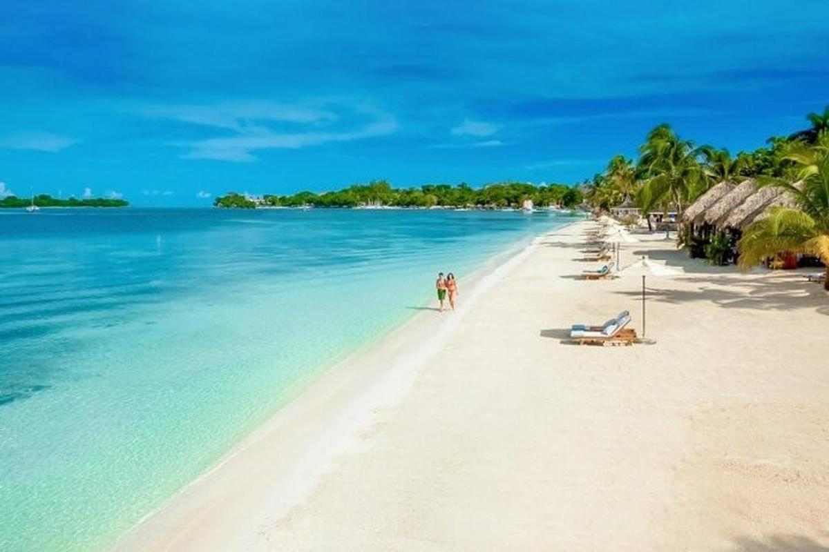 una spiaggia con persone in piedi sulla sabbia e sull'acqua