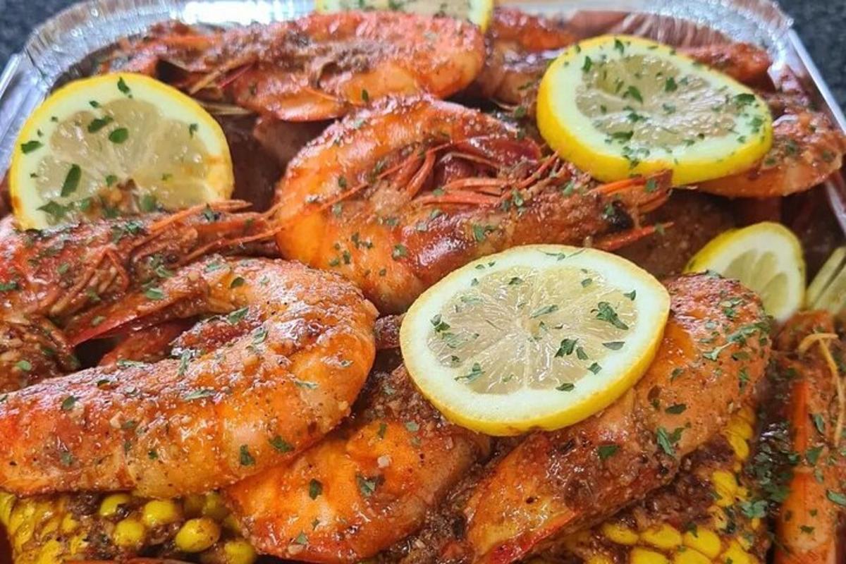 un piatto di cibo con gamberi, mais e fette di limone