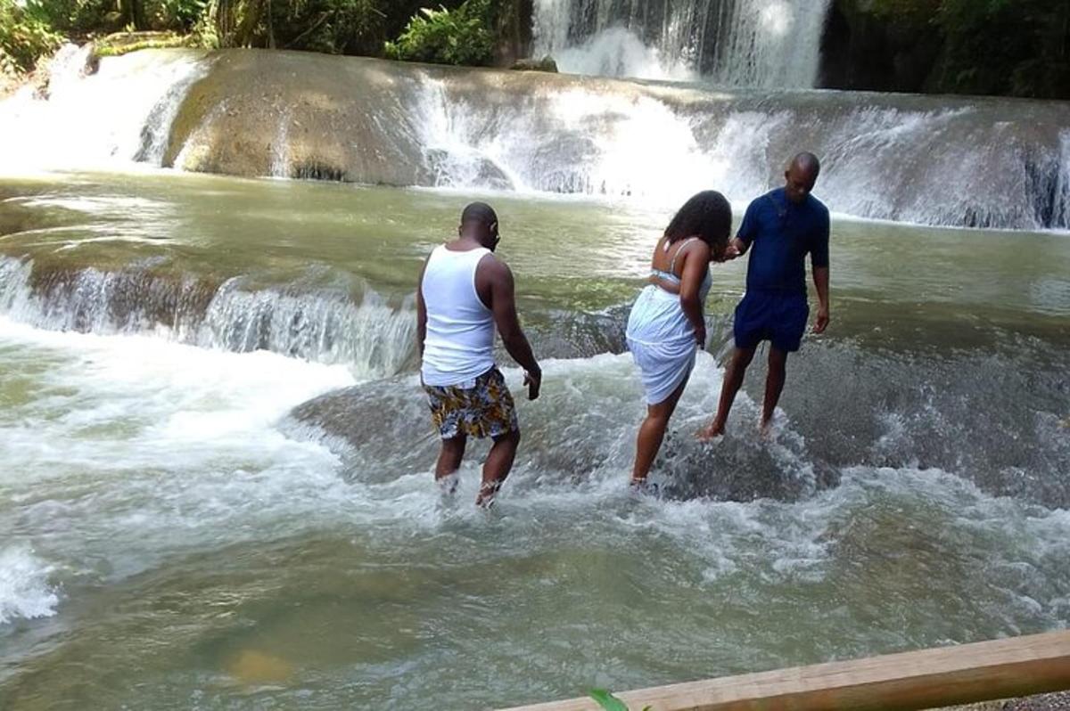 drei Personen stehen im Wasser in der Nähe eines Wasserfalls