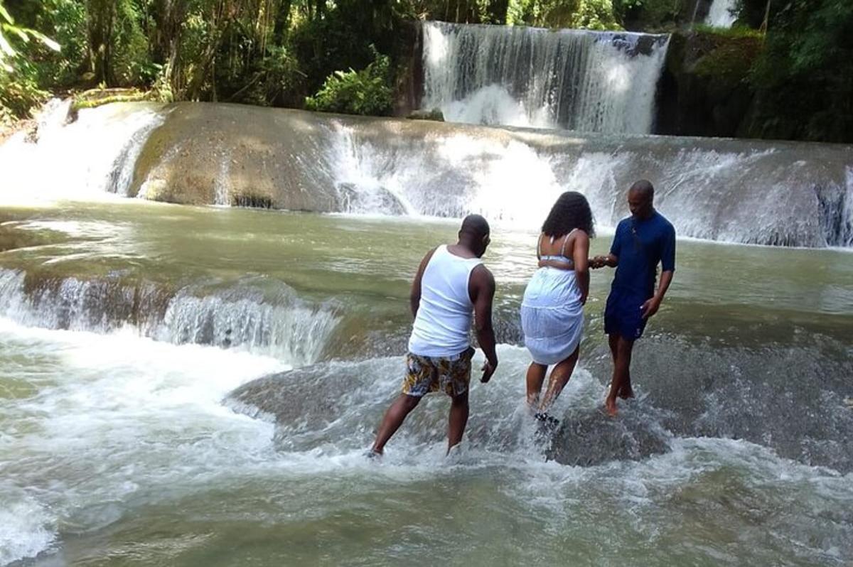 tre persone in piedi nell'acqua vicino a una cascata