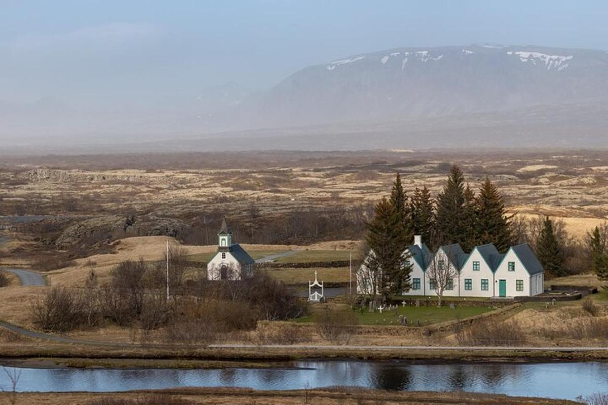 a large white house on a hill next to a lake