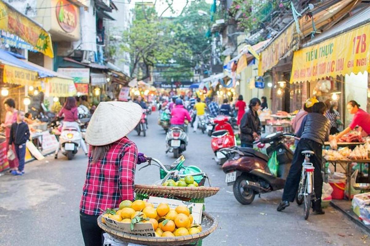 a woman walking down a street with baskets of oranges