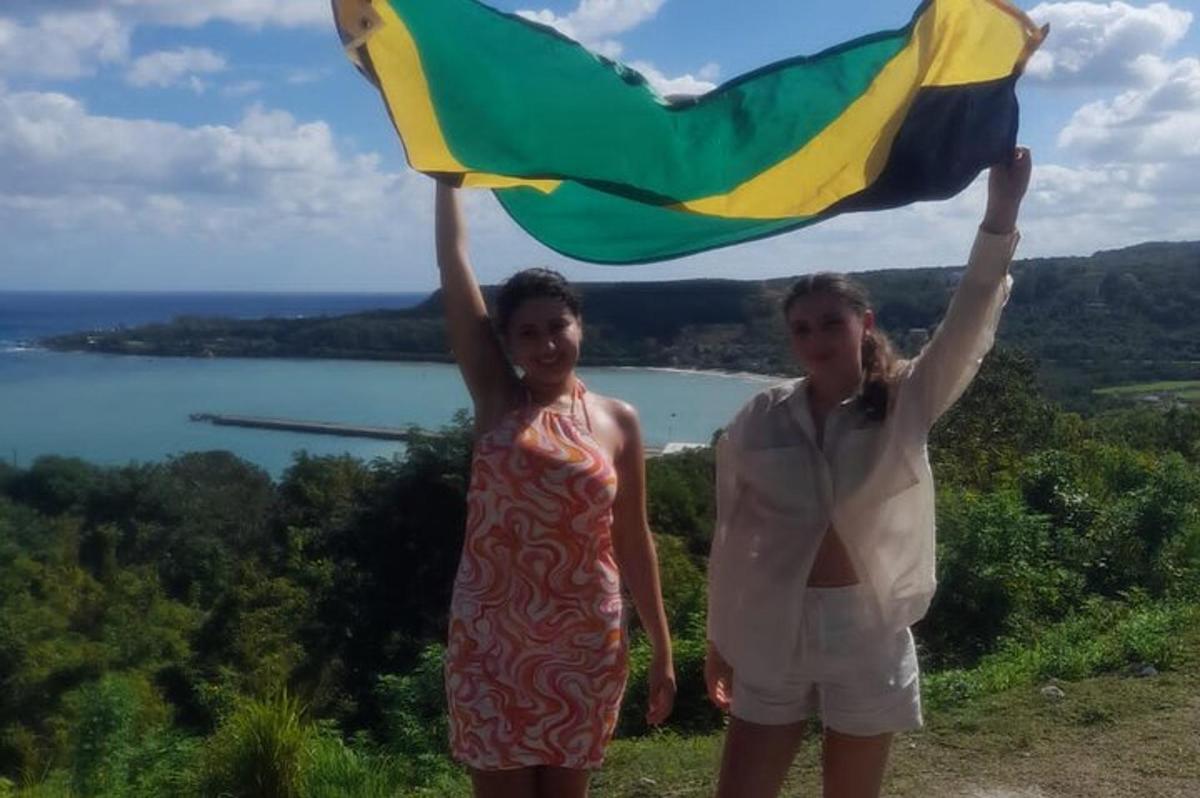 Dos mujeres de pie en una colina sosteniendo una bandera