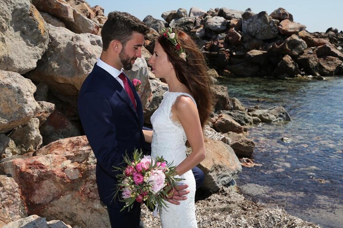 une mariée et un marié debout sur les rochers au bord de l'eau