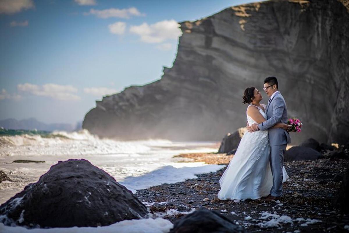 une mariée et un marié debout sur une plage rocheuse