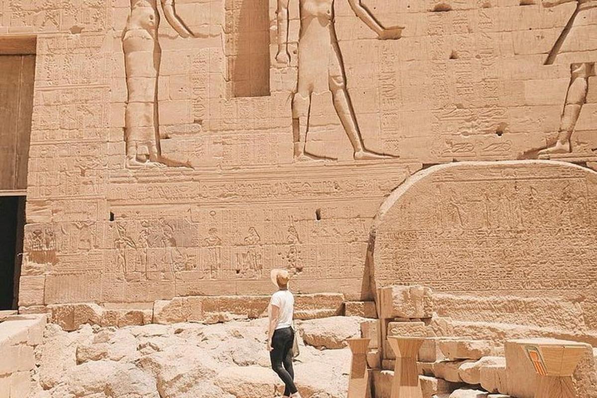 un homme debout devant un mur avec des statues