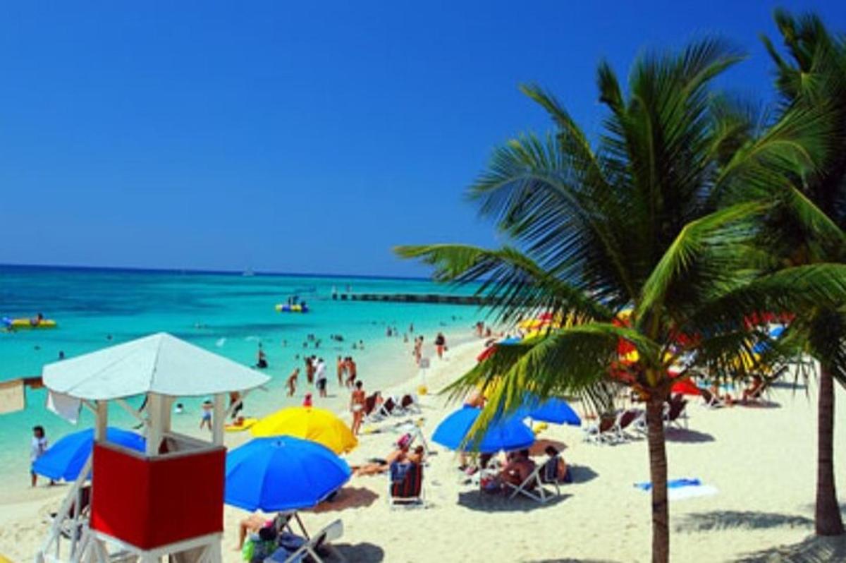 skupina ljudi na plaži s senčniki in oceanom
