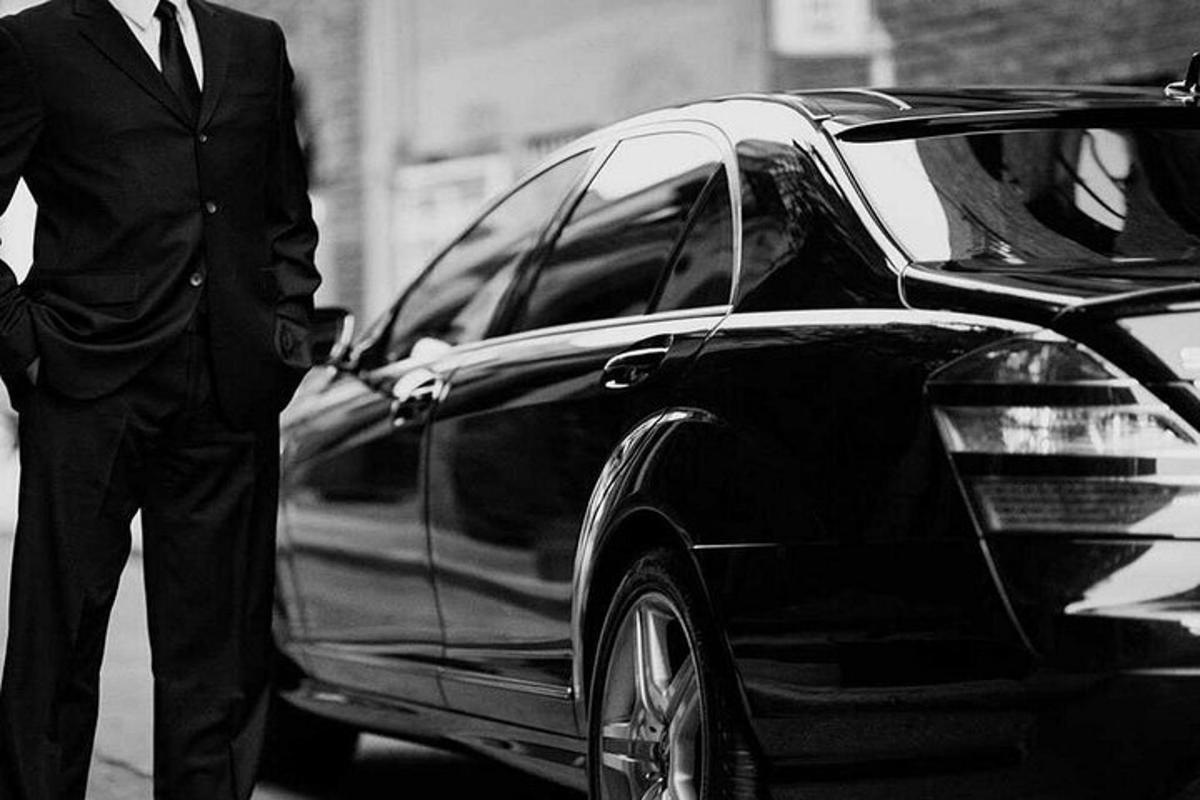 um homem de terno parado ao lado de um carro