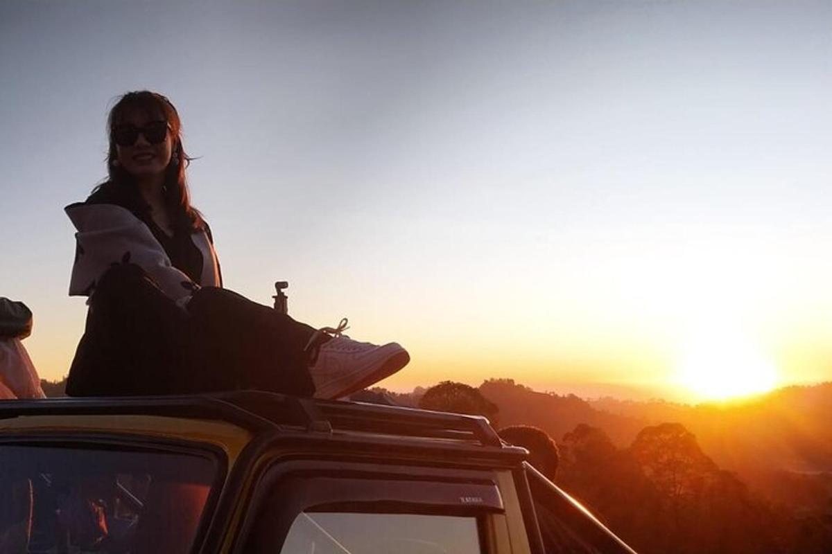 Una mujer sentada en el techo de un coche al atardecer