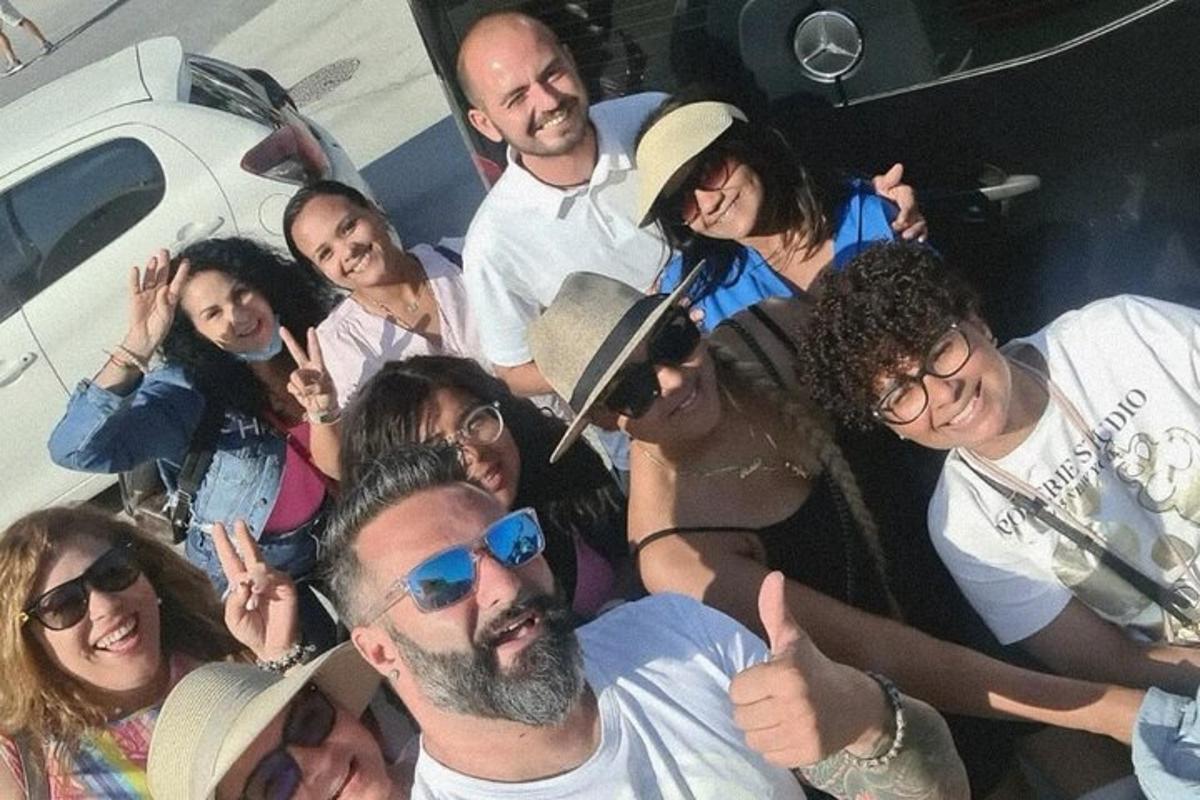 um grupo de pessoas posando para uma foto na frente de um carro