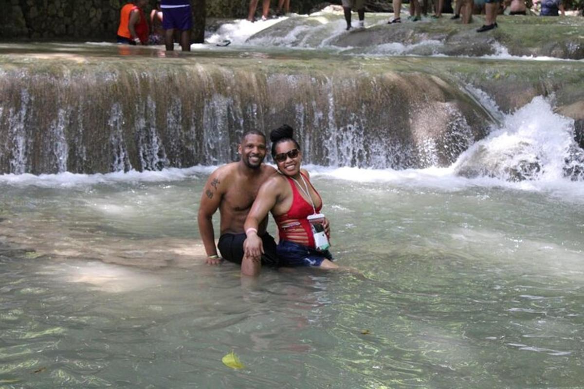 due persone sedute nell'acqua di fronte a una cascata