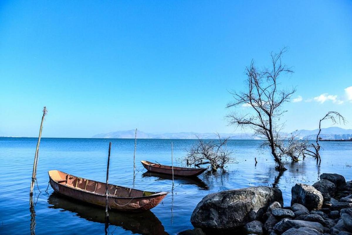 two boats sitting on the water near some rocks