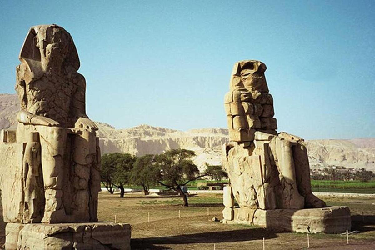 due statue di pietra in un campo con montagne sullo sfondo