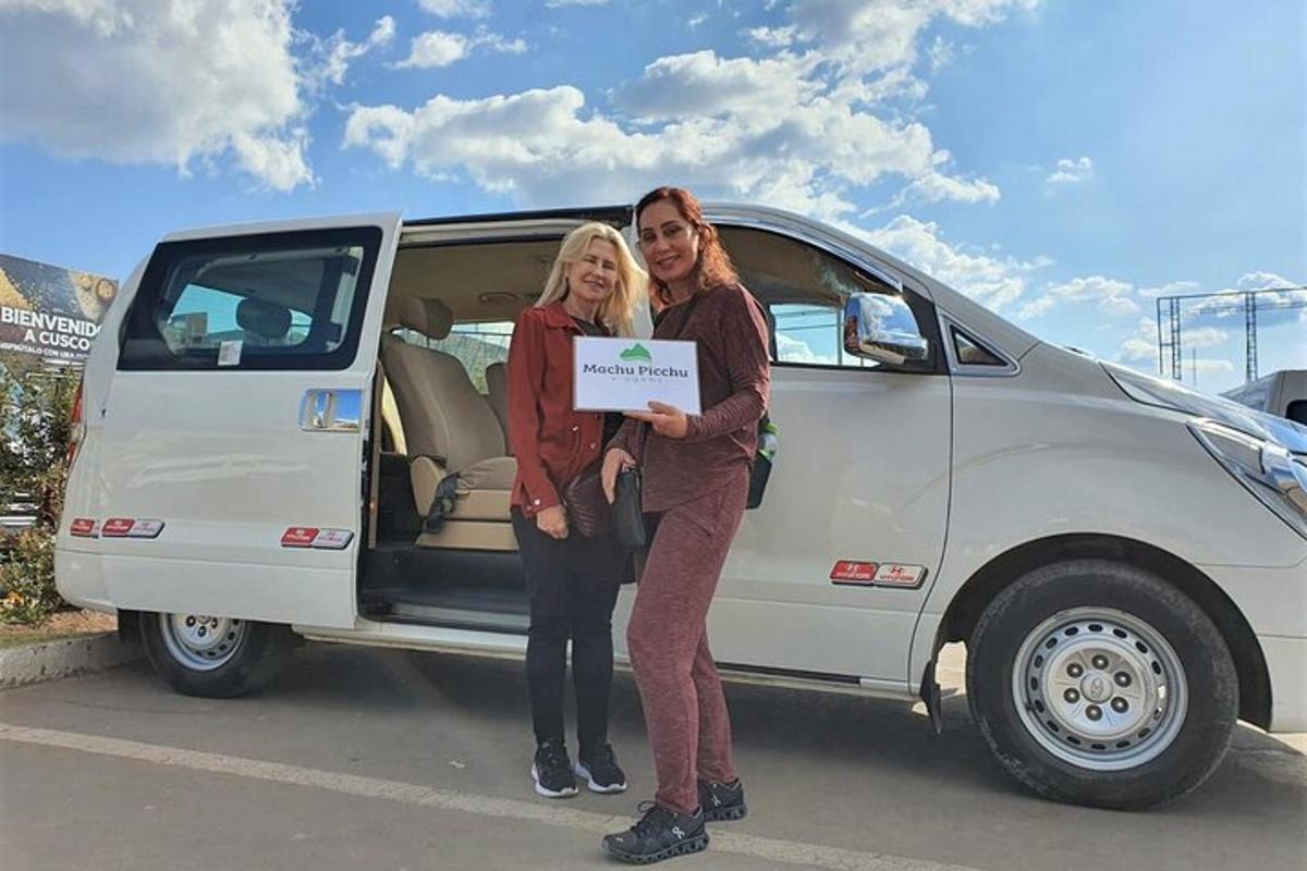 Un hombre y una mujer sosteniendo un cartel frente a una camioneta.