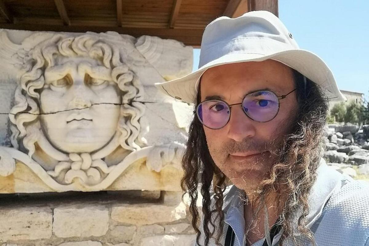 a man wearing a hat and sunglasses next to a statue