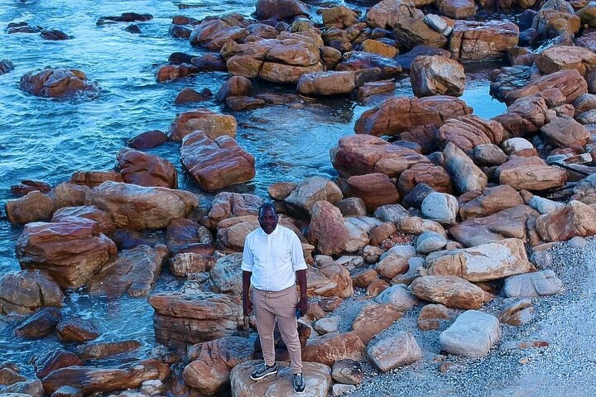 a man standing on a pile of rocks next to the water