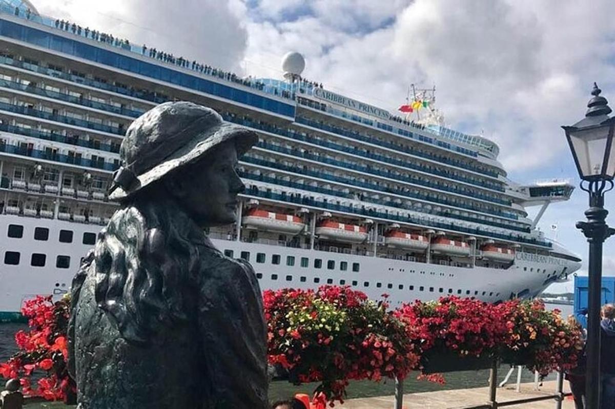 a statue of a woman in front of a cruise ship