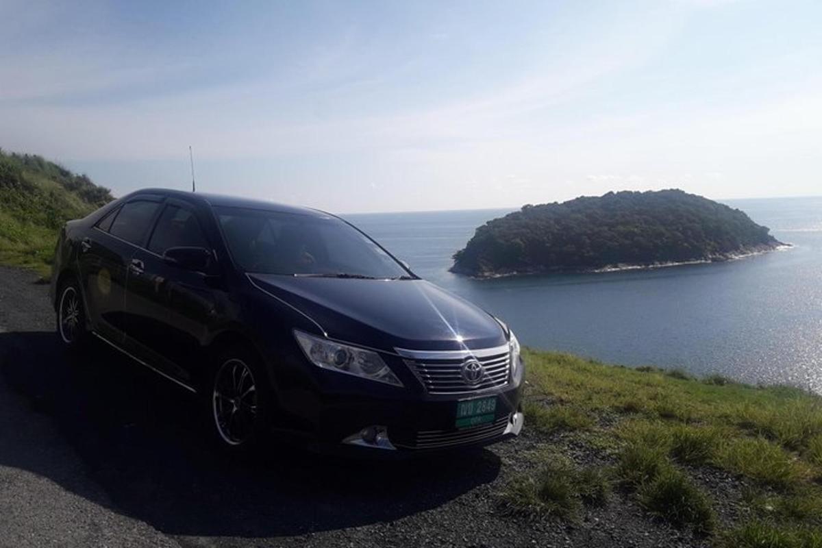 a black car parked on a hill near the ocean