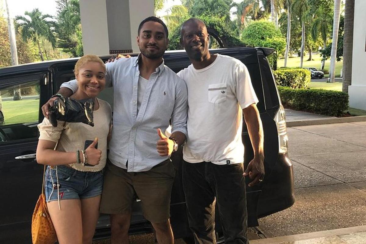 two men and a woman standing next to a car