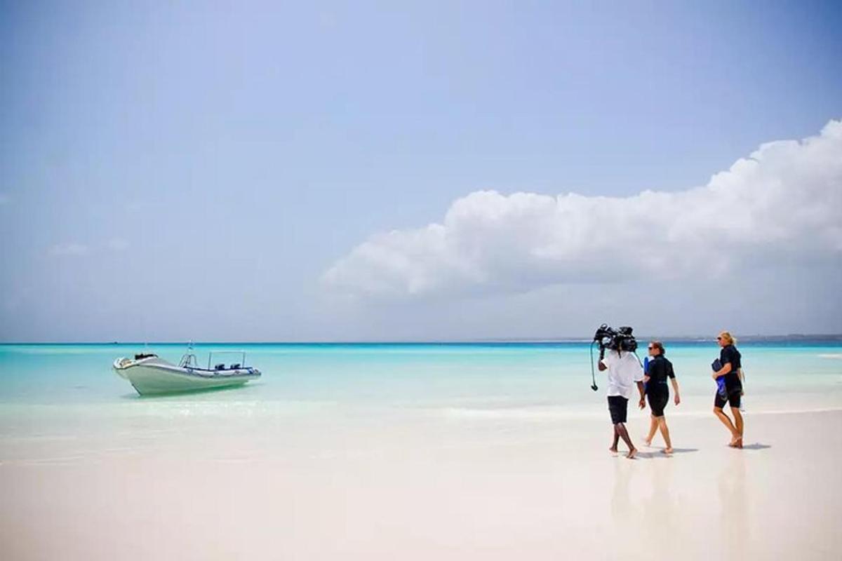 three people walking on a beach with a boat