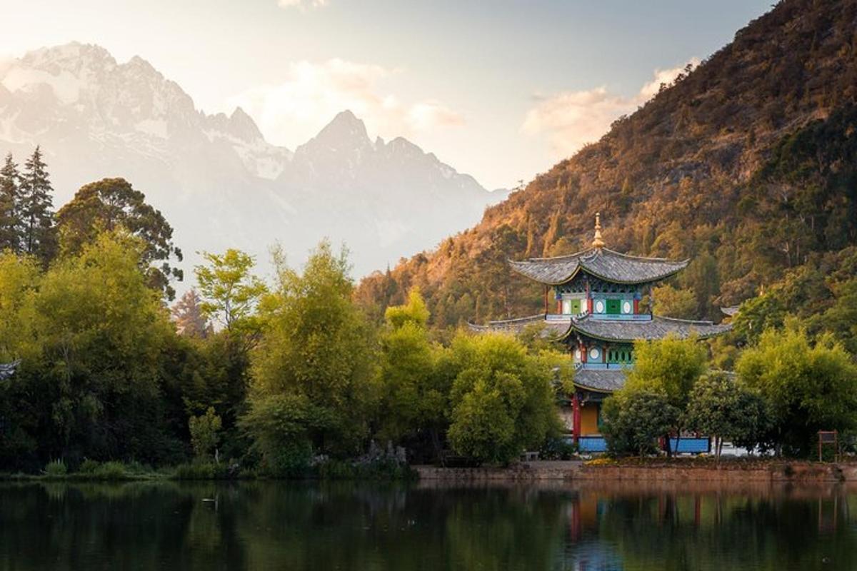 a building next to a lake with mountains in the background