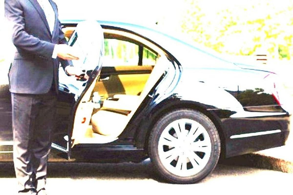 ülikonnas mees auto ust avamas
