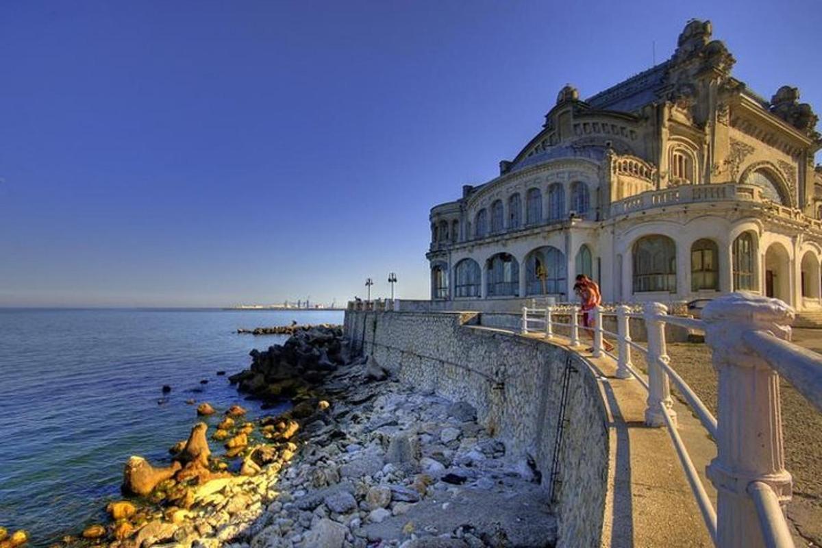 a large building next to the ocean with people standing on a ledge