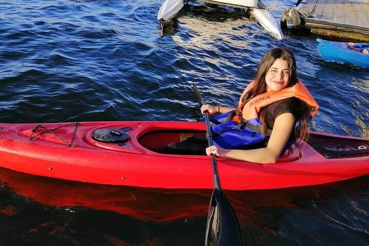 una donna seduta su un kayak rosso in acqua