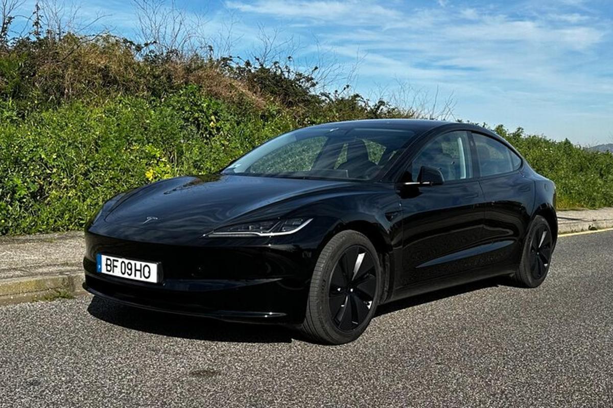 sebuah kereta tesla hitam memandu di jalan raya