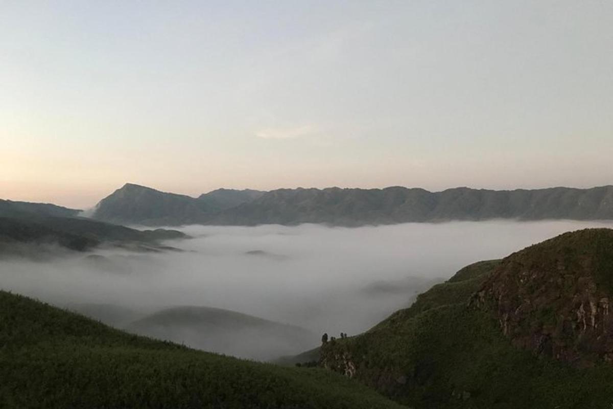 a view of a foggy valley with mountains in the background